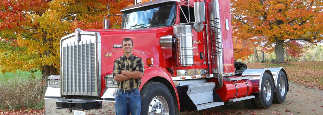 a young man stands in front of a red truck